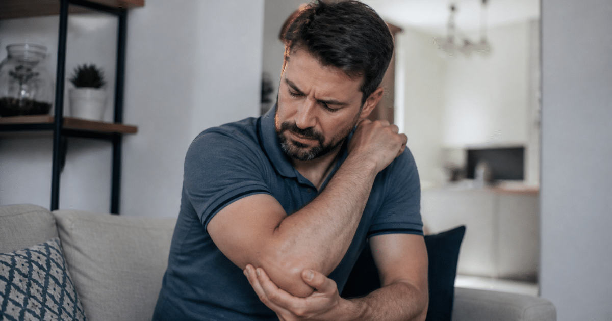 Homme tenant son coude douloureux contre son corps