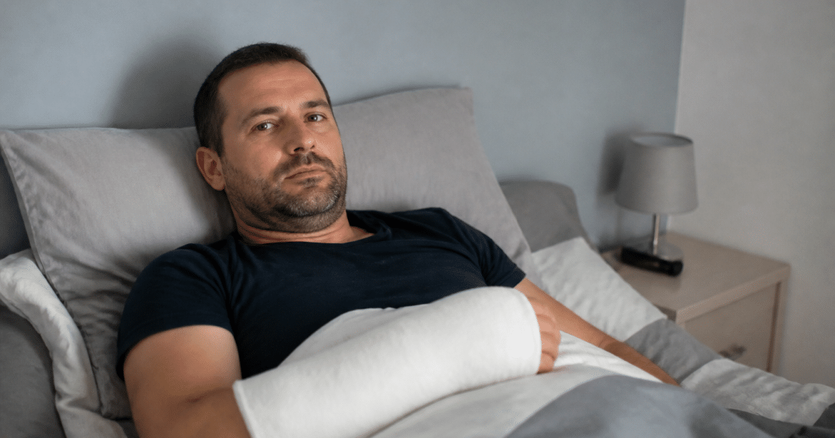 Homme immobilise au lit avec bras en plâtre blanc